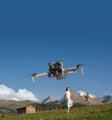 DJI Mini Drone flying over a scenic landscape with mountains and people on a grassy field, sold by a DJI Authorized Retailer.